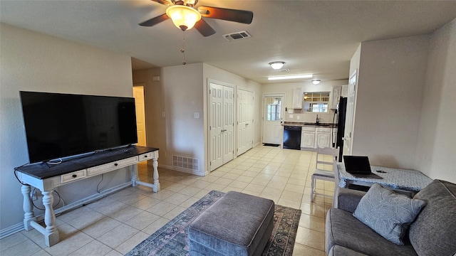 tiled living room with ceiling fan and sink