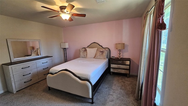 bedroom with multiple windows, ceiling fan, and dark colored carpet