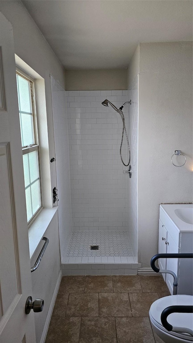 bathroom featuring a tile shower, vanity, and toilet