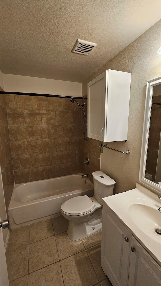 full bathroom with tile patterned flooring, a textured ceiling, toilet, vanity, and tiled shower / bath