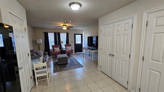 living room with ceiling fan, light tile patterned floors, and a textured ceiling