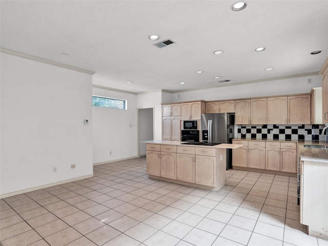 kitchen featuring black microwave, sink, stainless steel fridge, light brown cabinetry, and a kitchen island