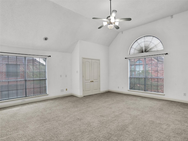 carpeted empty room featuring ceiling fan, a healthy amount of sunlight, a textured ceiling, and vaulted ceiling