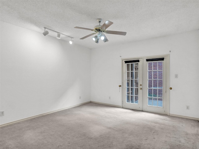 carpeted spare room with ceiling fan, french doors, track lighting, and a textured ceiling