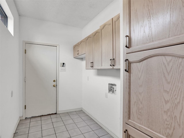 clothes washing area with hookup for a washing machine, light tile patterned floors, cabinets, and a textured ceiling