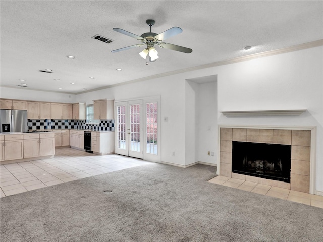 unfurnished living room featuring ceiling fan, crown molding, a textured ceiling, light carpet, and a fireplace