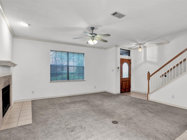 unfurnished living room featuring crown molding, light colored carpet, a tile fireplace, and ceiling fan