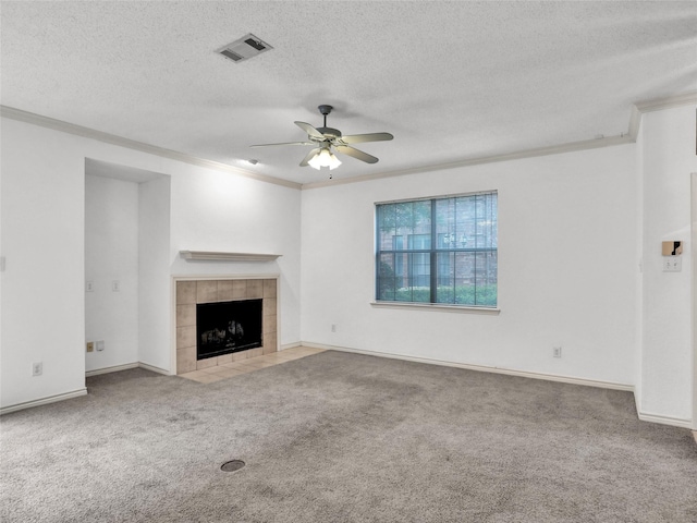 unfurnished living room with a tile fireplace, ceiling fan, ornamental molding, a textured ceiling, and light colored carpet