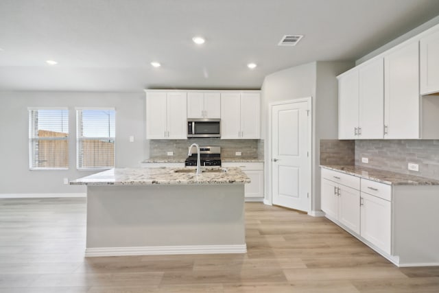 kitchen with light wood-type flooring, white cabinetry, and sink