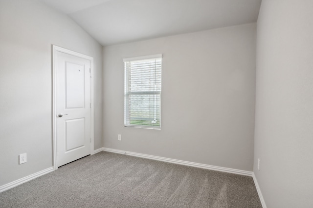 spare room with carpet and vaulted ceiling