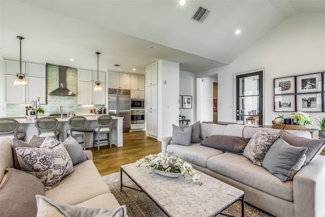 living room with high vaulted ceiling, recessed lighting, visible vents, and light wood-style floors