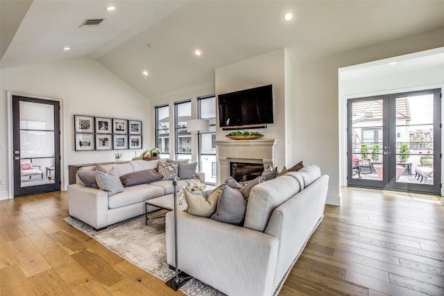 living area featuring french doors, visible vents, a fireplace, and light wood-style flooring