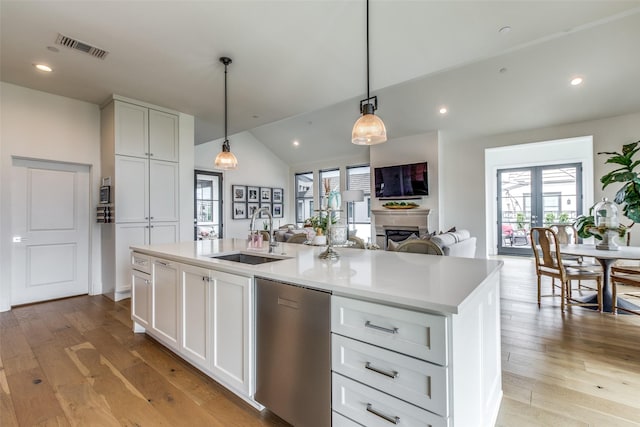 kitchen with visible vents, a sink, a kitchen island with sink, light wood-style floors, and stainless steel dishwasher