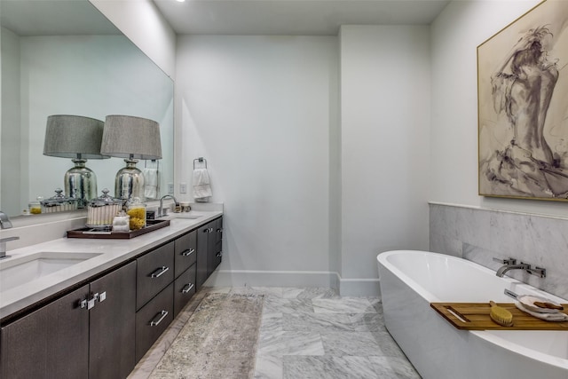 bathroom featuring double vanity, baseboards, marble finish floor, a freestanding bath, and a sink