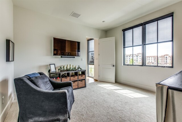 living area with light carpet, baseboards, and visible vents