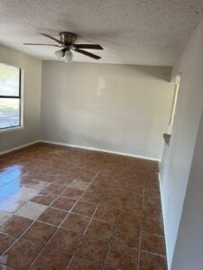 unfurnished room with ceiling fan and a textured ceiling