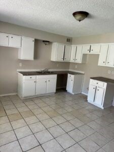 kitchen with a textured ceiling, white cabinetry, sink, and light tile patterned floors