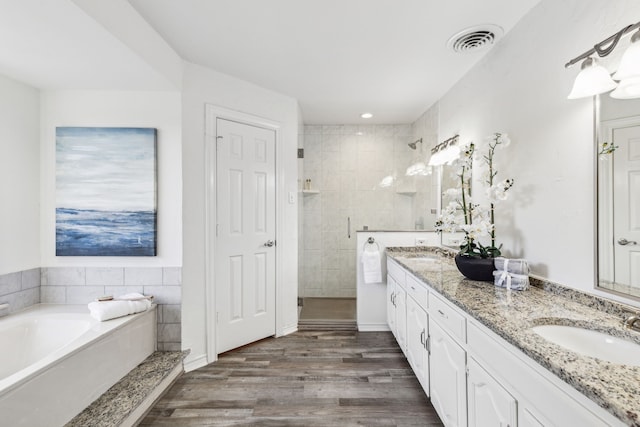 bathroom with hardwood / wood-style floors, vanity, and plus walk in shower