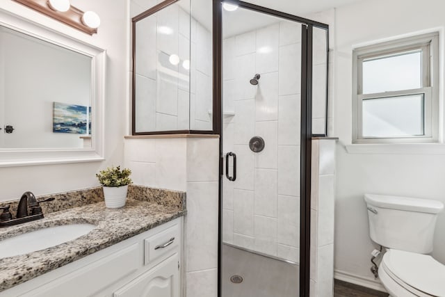 bathroom with hardwood / wood-style floors, vanity, toilet, and a shower with door