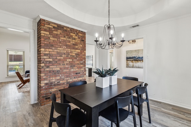 dining space featuring wood-type flooring, a tray ceiling, and ornamental molding