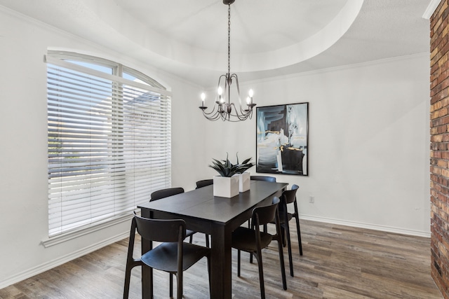 dining room featuring a chandelier, a tray ceiling, crown molding, and dark wood-type flooring