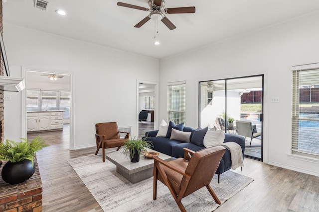 living room with ceiling fan, light wood-type flooring, a fireplace, and a wealth of natural light