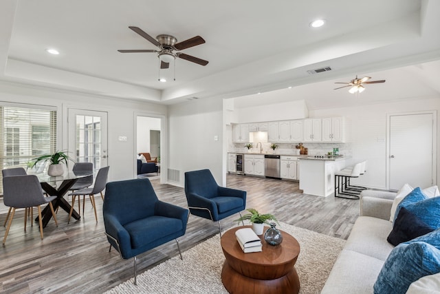 living room with hardwood / wood-style floors, a raised ceiling, and beverage cooler