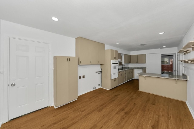 kitchen with a kitchen breakfast bar, sink, cream cabinetry, light stone counters, and wood-type flooring