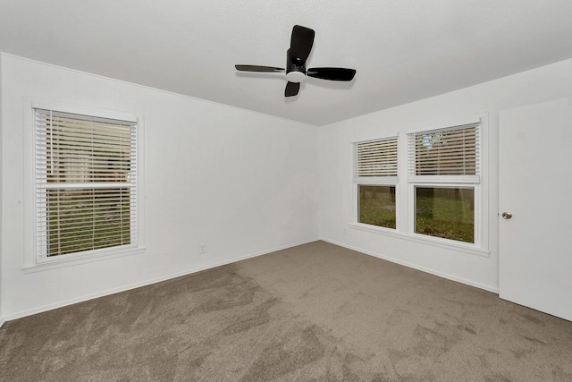 spare room with ceiling fan and dark colored carpet