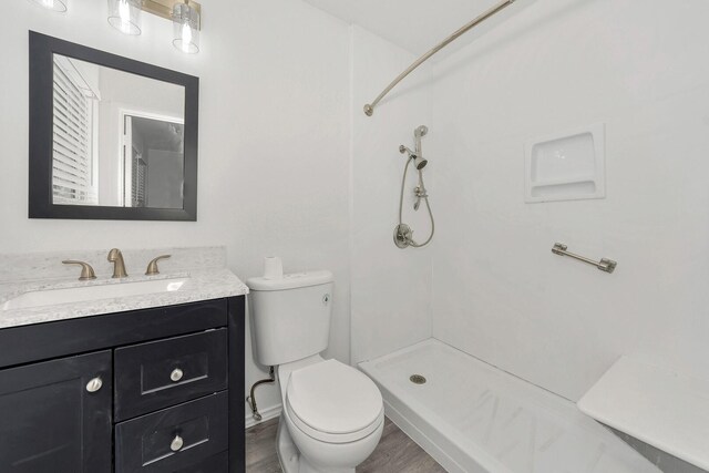 bathroom featuring vanity, a tile shower, and toilet