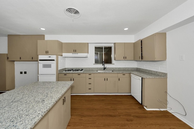 kitchen with sink, dark hardwood / wood-style flooring, decorative backsplash, light stone countertops, and white appliances