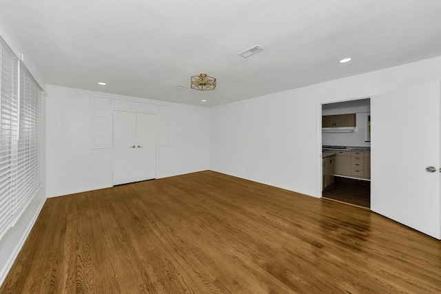 unfurnished bedroom with a closet, ensuite bathroom, and hardwood / wood-style floors