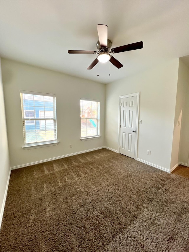 empty room featuring ceiling fan and dark colored carpet