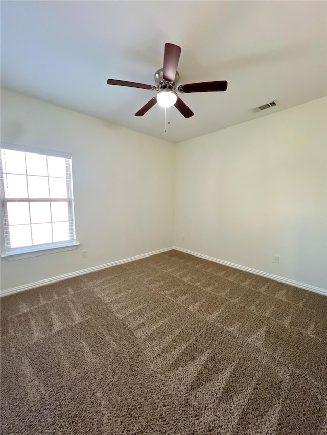 unfurnished room with ceiling fan and dark colored carpet