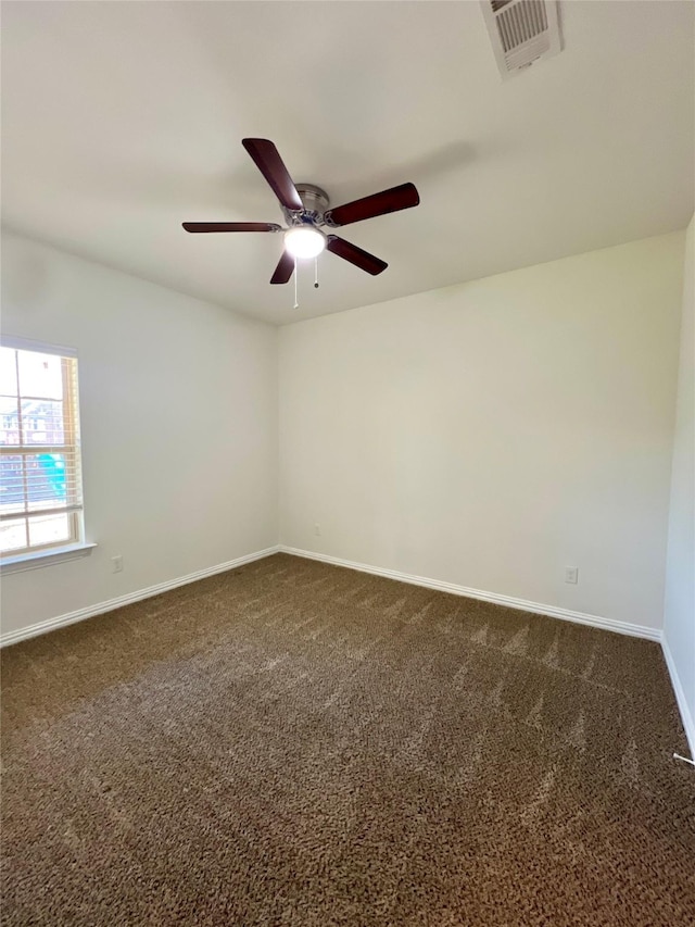 spare room featuring ceiling fan and dark carpet