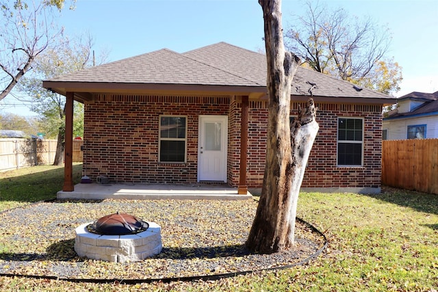 rear view of property with a fire pit and a yard