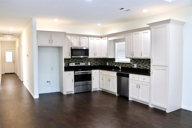 kitchen featuring white cabinets, a wealth of natural light, dark wood-type flooring, and appliances with stainless steel finishes