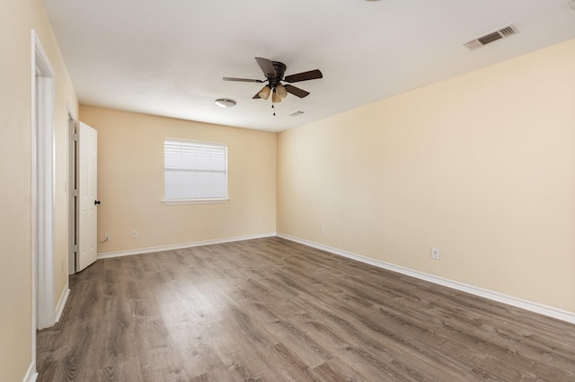 unfurnished room with visible vents, ceiling fan, baseboards, and wood finished floors