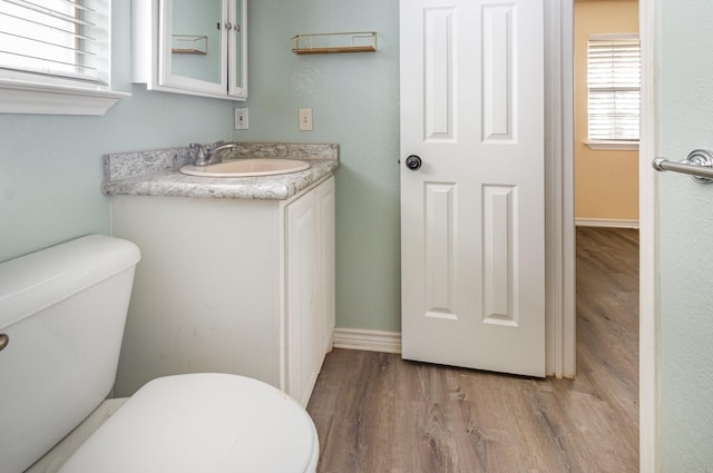 bathroom featuring vanity, wood finished floors, toilet, and baseboards