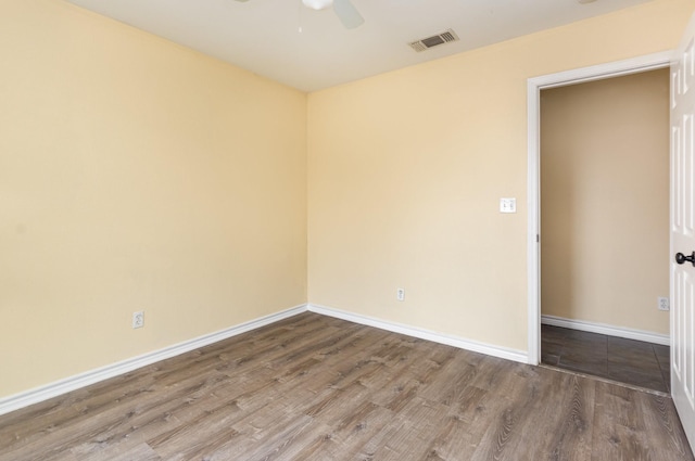 empty room with a ceiling fan, wood finished floors, visible vents, and baseboards