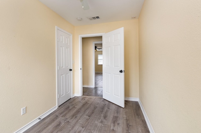 hallway featuring visible vents, baseboards, and wood finished floors