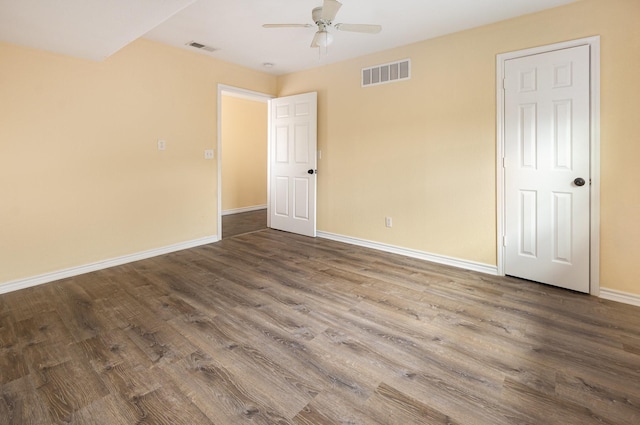 empty room with a ceiling fan, baseboards, visible vents, and wood finished floors