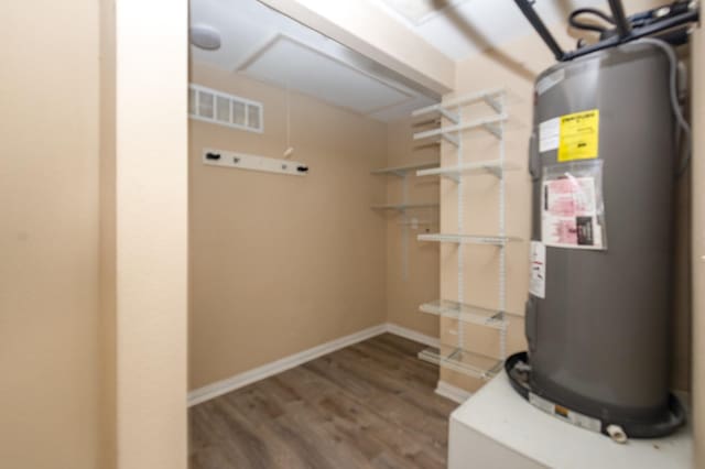 utility room with electric water heater and visible vents