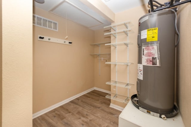 utility room with electric water heater and visible vents