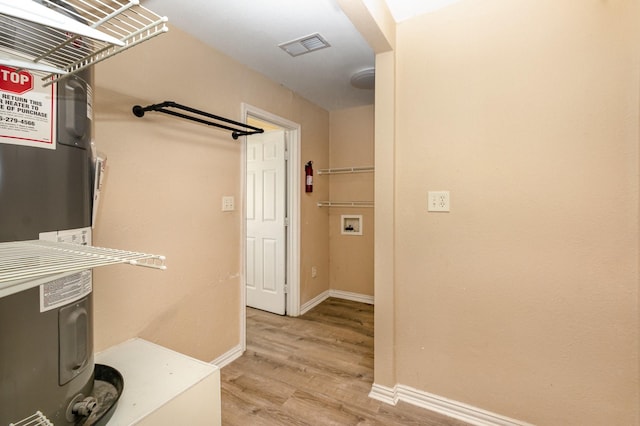 hall with light wood-style floors, visible vents, and baseboards