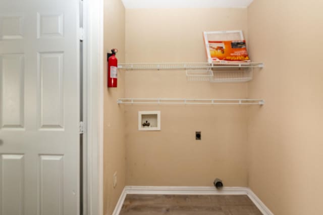 washroom with hookup for a washing machine, hookup for an electric dryer, laundry area, wood finished floors, and baseboards