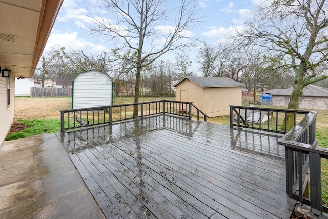 wooden terrace with a lawn, an outdoor structure, fence, and a storage unit