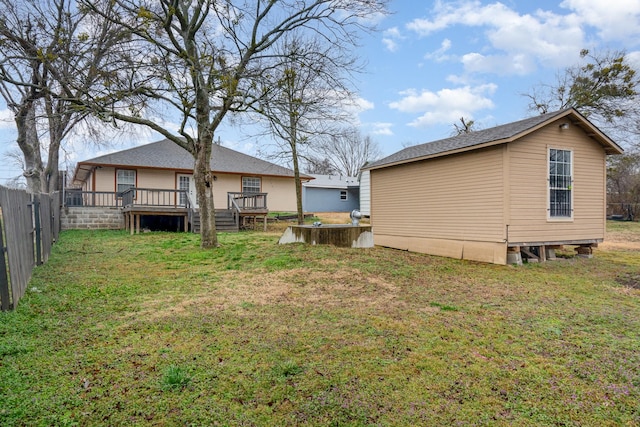 rear view of house with a lawn, a wooden deck, and fence