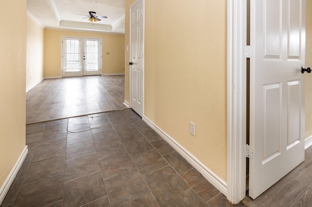 hall featuring french doors, a raised ceiling, crown molding, and baseboards