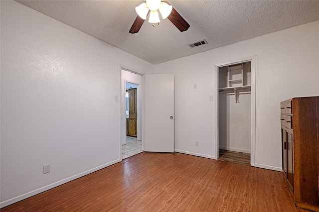 unfurnished bedroom with ceiling fan, a closet, light hardwood / wood-style flooring, and a textured ceiling